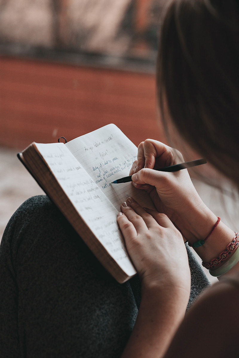 Young woman reflecting and writing in her journal