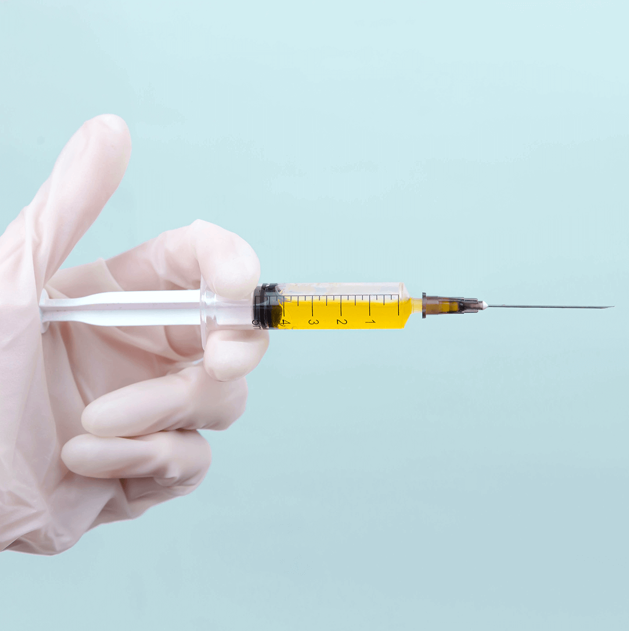 Doctor's hand holding a needle with medication inside